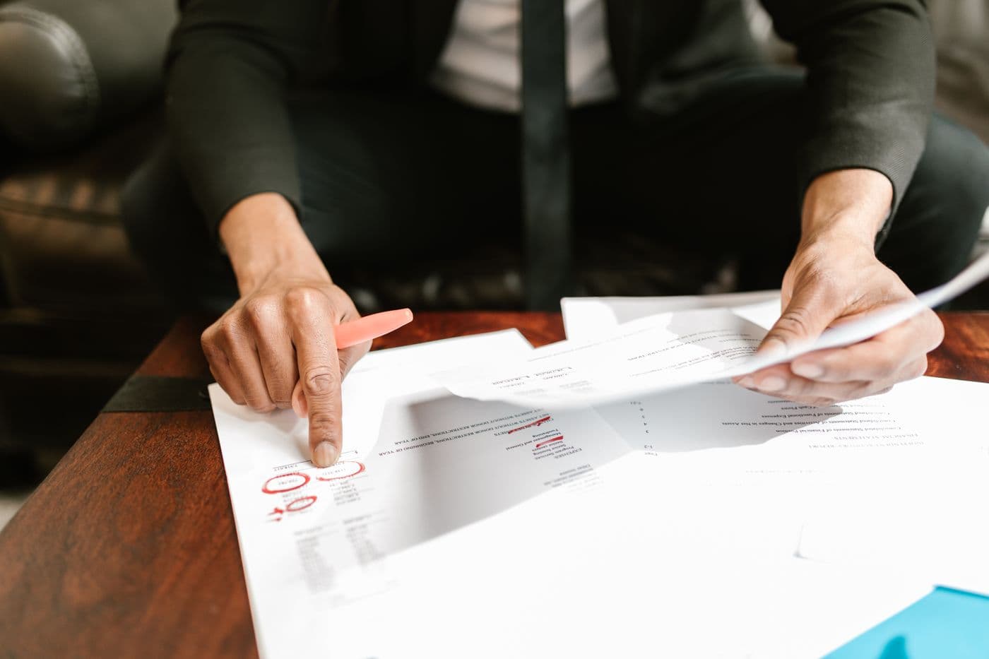 A professional reviewing financial reports at a desk, pen in hand