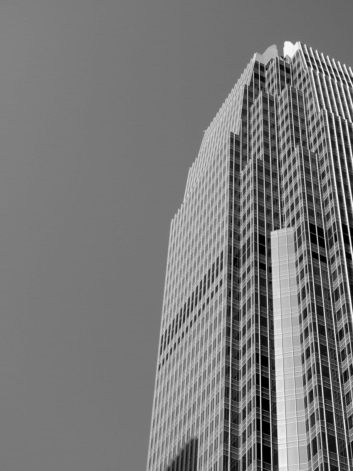 Black-and-white view up the glass facade of a commercial office tower