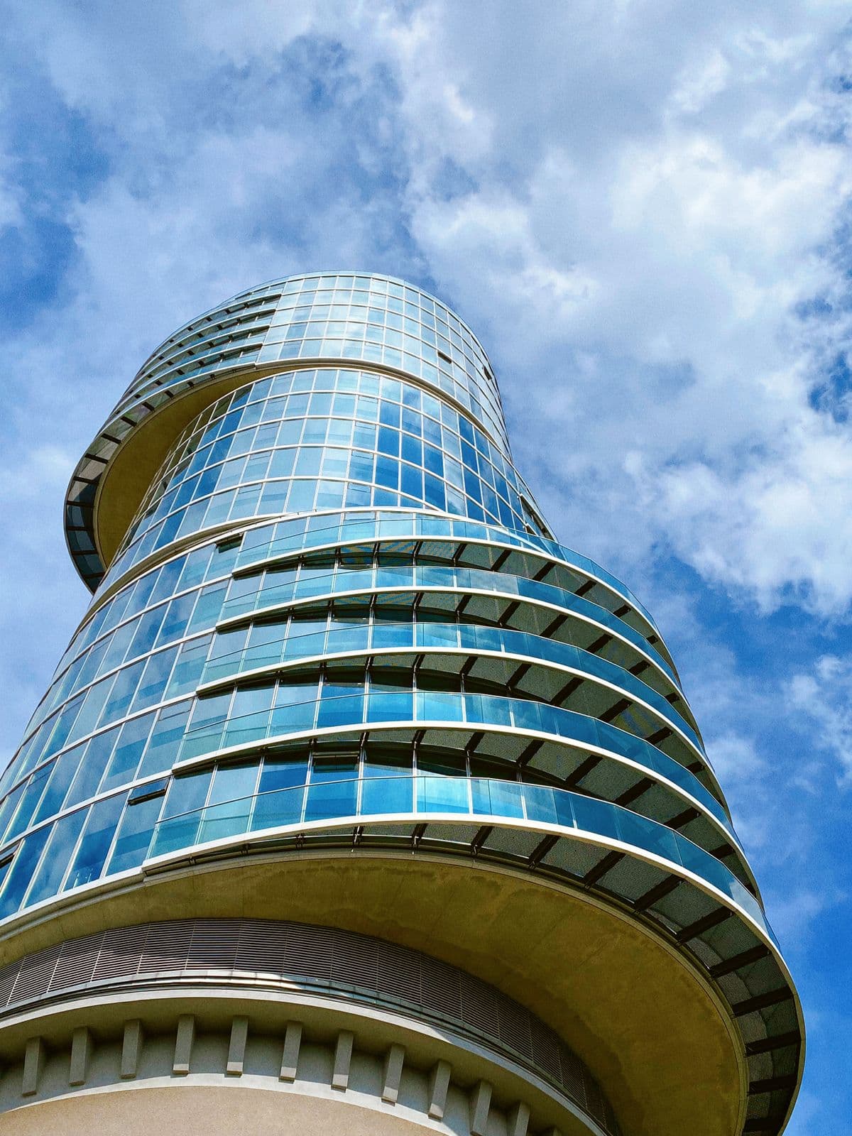 Looking up the curved glass facade of a modern commercial tower
