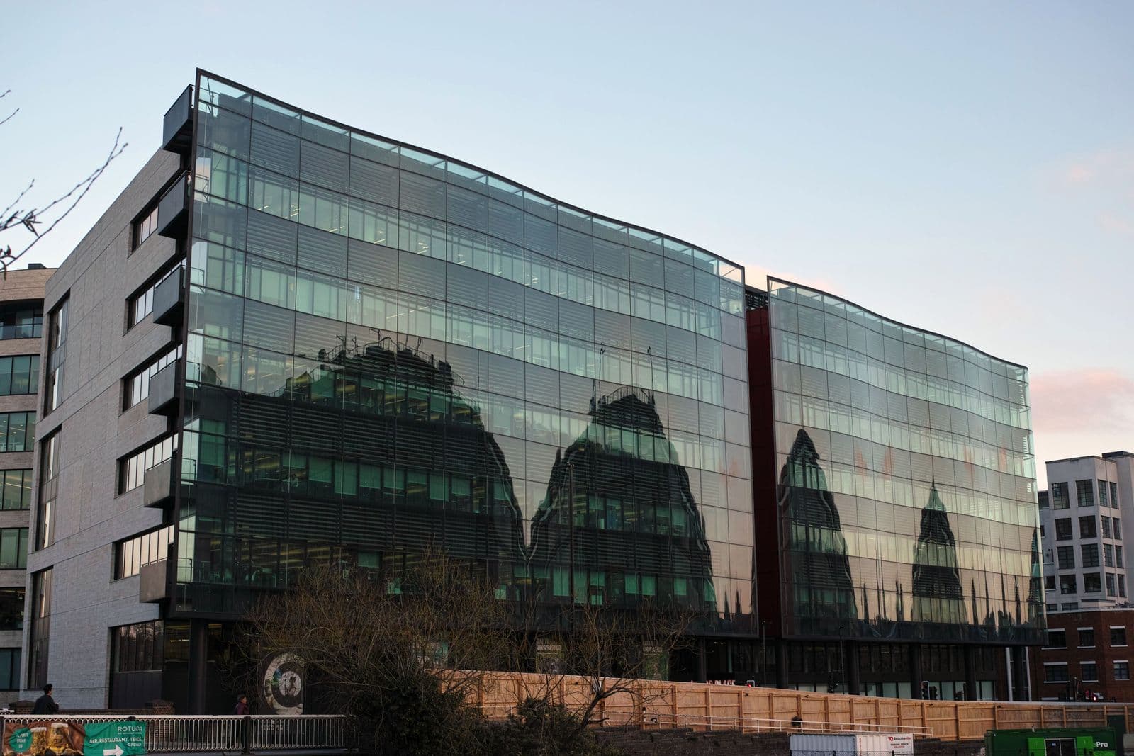 Glass-fronted office building with reflections of the surrounding architecture