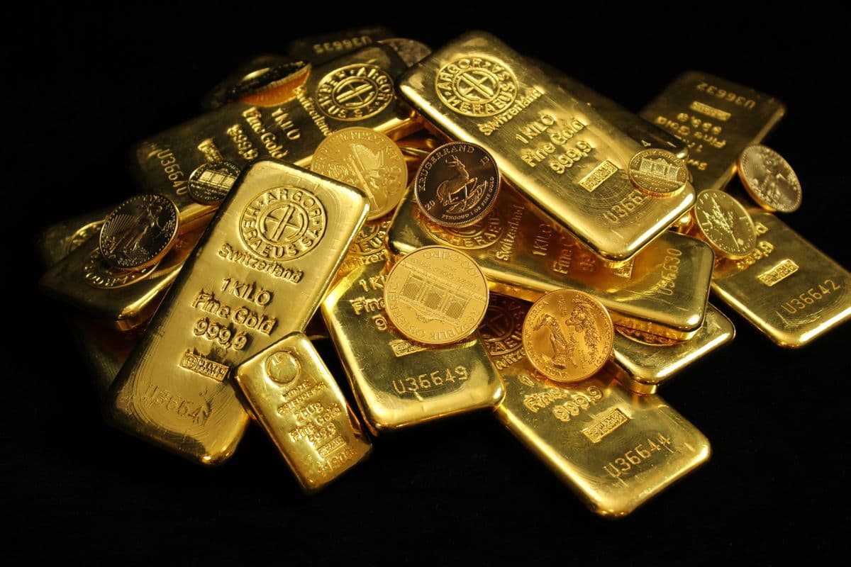A pile of gold bars and coins on a black background